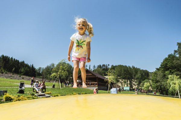 Holčička skákající na nafukovací trampolíně v Farmaparku Soběhrdy